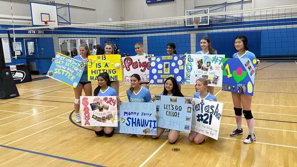 Un grupo de alumnas de la Seaquam Secondary School sostiene pancartas coloridas en la cancha de baloncesto.