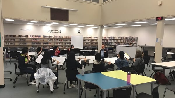 Alumnos de la Seaquam Secondary School trabajan en la biblioteca en mesas con libros y materiales.