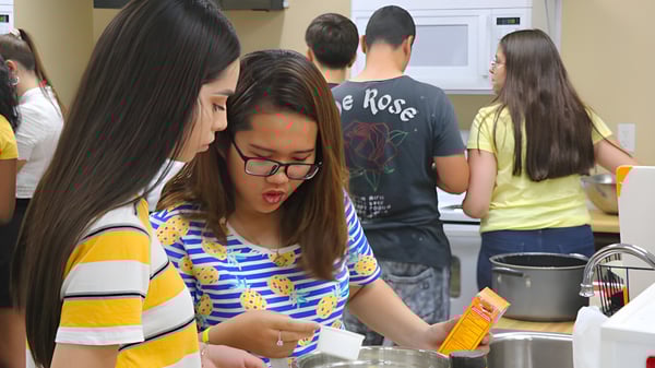 Un grupo de estudiantes de la Sequoia Charter High School está reunido en la cocina realizando diversas actividades.