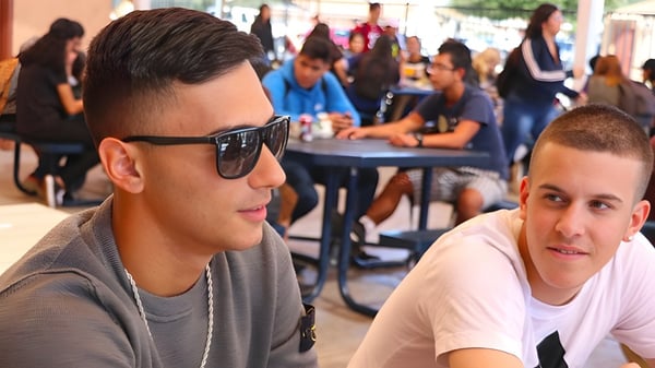 Dos jóvenes están sentados en una mesa en un área al aire libre en el campus de la Sequoia Charter High School.