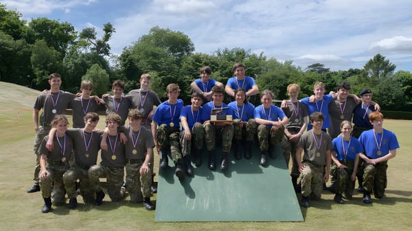 Un grupo de estudiantes de la Sevenoaks School está en una wiese con árboles de fondo.