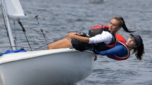 Dos personas navegan en un pequeño barco sobre el agua en el fondo de la Sevenoaks School.