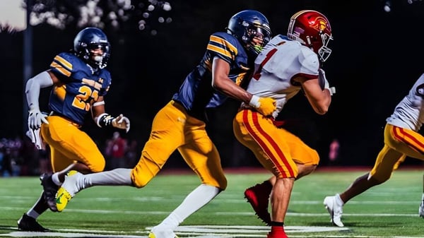 Dos jugadores de fútbol en el campo de la Shady Side Academy durante un partido al atardecer.