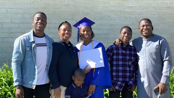 Un grupo de estudiantes, incluyendo a una persona en toga de graduación, frente a una pared de ladrillo en el campus de Shaftesbury High.