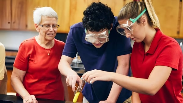 Tres estudiantes de la Shalom Christian Academy trabajan juntos en una cocina con revestimiento de madera.