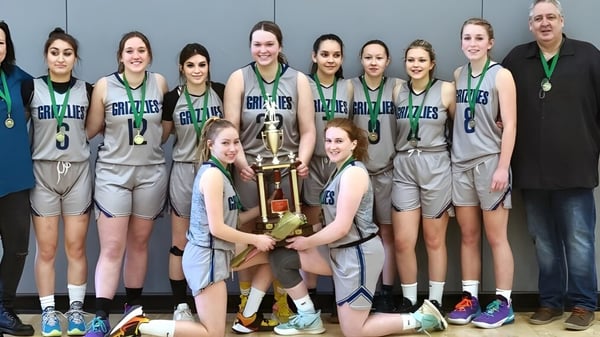 Estudiantes de la Shas Ti Kelly Road Secondary School posan con un trofeo en el gimnasio.