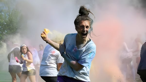 Una persona está cubierta de polvo de colores en el campus de la Shattuck-St. Mary's School y está rodeada de otras personas.