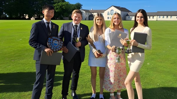 Un grupo de cinco estudiantes está en un prado frente al edificio del Shebbear College.