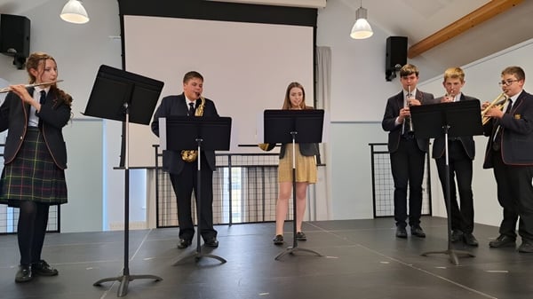 Estudiantes del Shebbear College están vestidos de forma formal en el escenario y presentan una actuación.