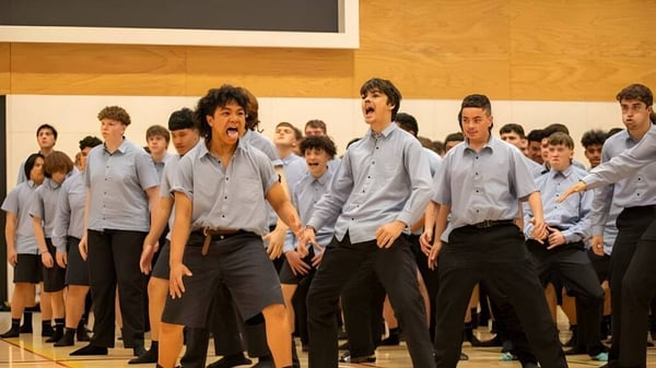 Un grupo de estudiantes de Shirley Boys' High School está en fila frente a un escenario de madera.