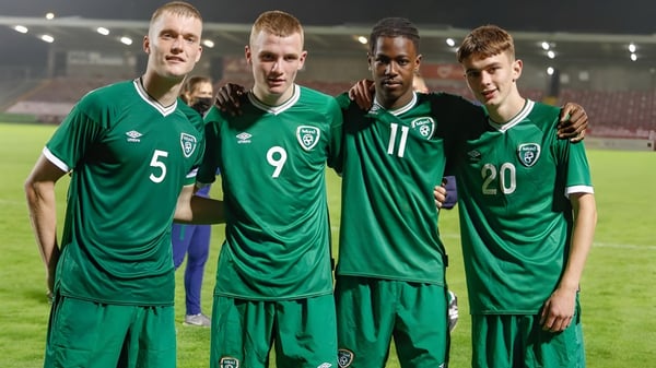 Cuatro futbolistas en camisetas verdes están en el campo de fútbol de la Sibford School bajo las luces.
