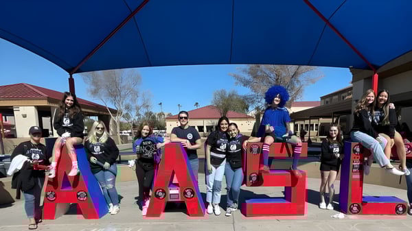 Un grupo de estudiantes en trajes coloridos posa frente a grandes letras rojas con la inscripción CASA en el Sierra Vista Unified School District.