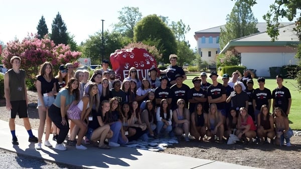 Un gran grupo de estudiantes se encuentra en el parque del campus de la Simpson University.