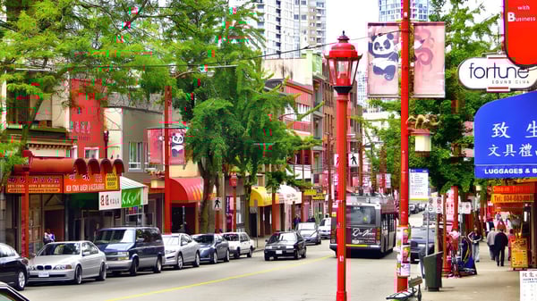 Una calle concurrida con tiendas coloridas y faroles rojos frente a edificios altos cerca de la Sir Charles Tupper Secondary School.