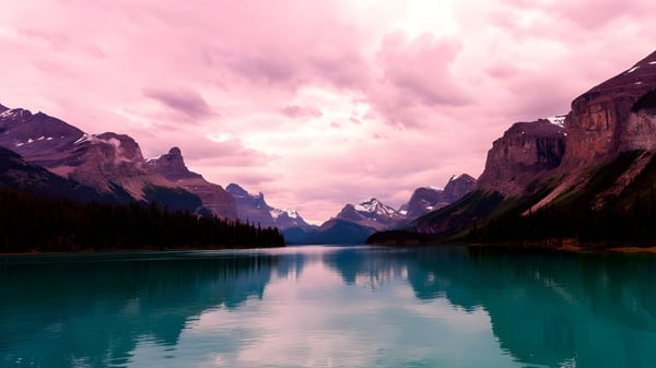 Un lago tranquilo con agua turquesa frente a montañas cubiertas de nieve en el terreno de la Sir Frederick Banting Secondary School.