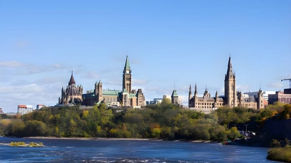 Un pintoresco paisaje urbano con río y edificios históricos ante el fondo de un cielo azul.