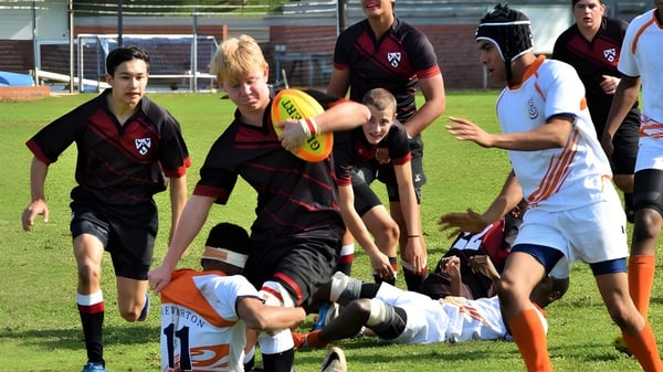 Estudiantes del Slindon College participan en una actividad deportiva en un campo de hierba.