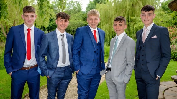 Cinco estudiantes del Slindon College están juntos en un área verde al aire libre con sauces al fondo.