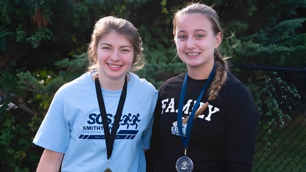 Dos estudiantes de la Smithtown Christian School están riendo juntas en un área verde exterior.