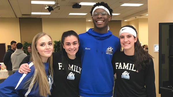 Un grupo de cuatro personas está juntas en una sala de la Smithtown Christian School y sonríe.