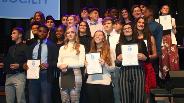 Estudiantes de la Smithtown Christian School reciben un premio en el escenario frente al fondo de la Society.