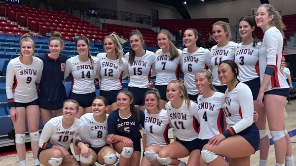 Un grupo de jóvenes jugadoras de voleibol posan en camisetas blancas de Snow College en una cancha de baloncesto.