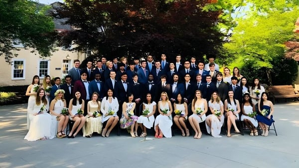 Un grupo de estudiantes de la Solebury School está vestido formalmente frente a un edificio con árboles verdes.