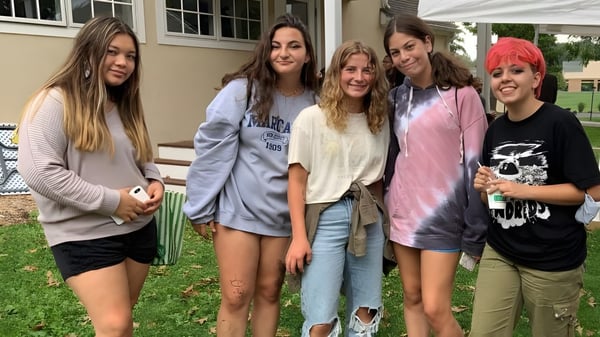 Un grupo de cinco estudiantes se encuentra afuera frente a un edificio en el campus de la Solebury School.