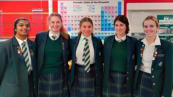 Cinco estudiantes del Solway College están frente a una pared con la tabla periódica de los elementos.
