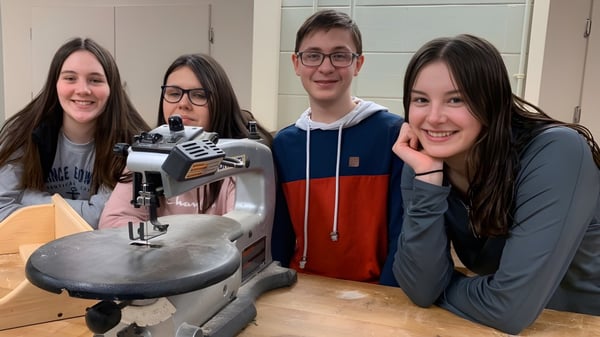 Cuatro estudiantes de la Souris Regional School están grabando en un estudio con un micrófono.