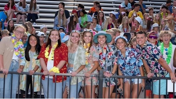 Un grupo de estudiantes de la South Christian High School posan juntas frente a un edificio detrás de una barandilla de metal.