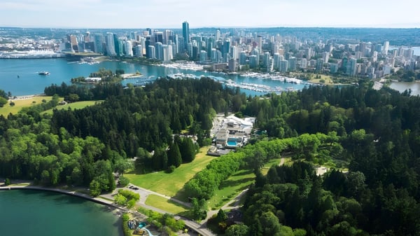 Un paisaje urbano extenso con modernos rascacielos se ve frente a un área boscosa.