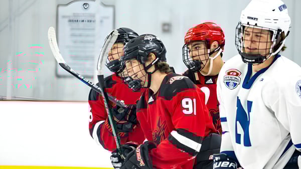 Un grupo de jugadores de hockey con camisetas rojas y azules está en la pista de hielo de la South Kent School.