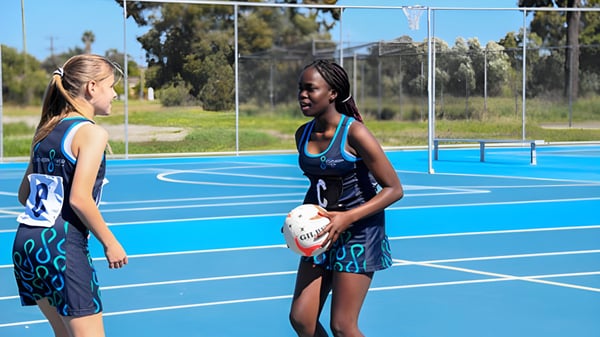 Dos alumnas en ropa deportiva están en la cancha de baloncesto al aire libre en el Southern River College.