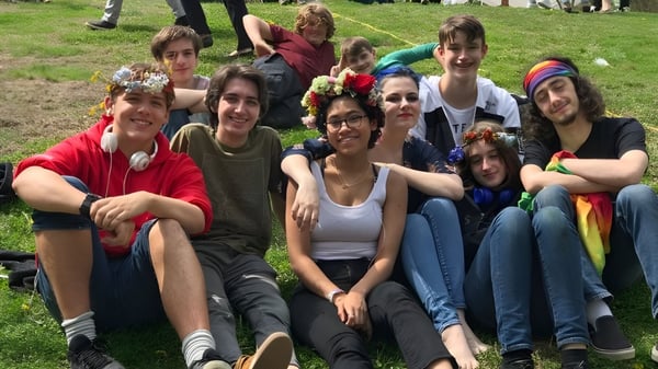 Un grupo de estudiantes se sienta juntos en el césped en un área exterior de la Sparhawk School.