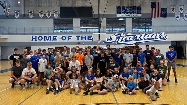 Un grupo de estudiantes se reúne en la cancha de baloncesto en el gimnasio de Sparta High School.