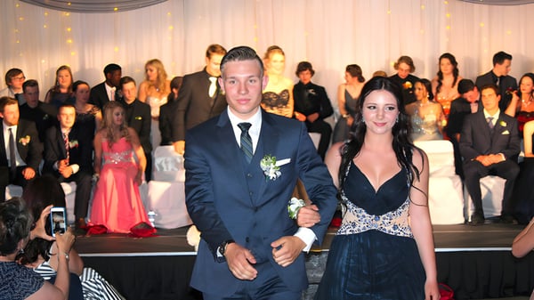 Una pareja en ropa formal está en un evento en el campus de la Sparwood Secondary School frente a una multitud.