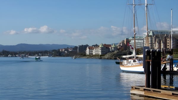 Vista del puerto y los veleros cerca de la Spectrum Community Secondary School frente a un paisaje montañoso.