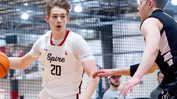 Dos estudiantes de la SPIRE Academy juegan baloncesto en una cancha al aire libre con un panorama urbano de fondo.