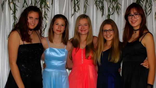 Cinco jóvenes mujeres en ropa formal posan juntas frente a una cortina en el campus de la Springbank School.