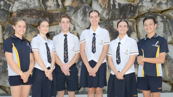 Seis estudiantes de la Springfield Central State High School están frente a un panorama montañoso rocoso.