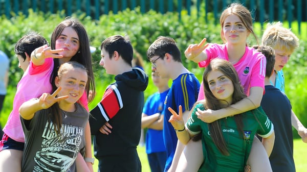 Un grupo de estudiantes se encuentra en un prado frente a unos árboles en el terreno de St Ailbe's School.