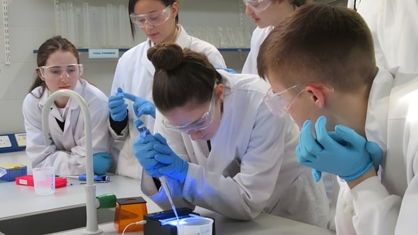 Estudiantes del St. Andrew's College trabajan en el laboratorio con equipo científico y materiales en una mesa.