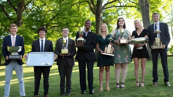 Un grupo de estudiantes de la St. Andrew's-Sewanee School está al aire libre sosteniendo premios y trofeos.