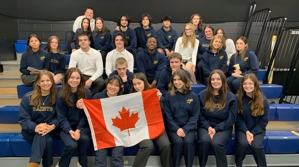Un grupo de alumnas en uniformes de la St. Anne Catholic High School sostiene juntas una bandera canadiense.