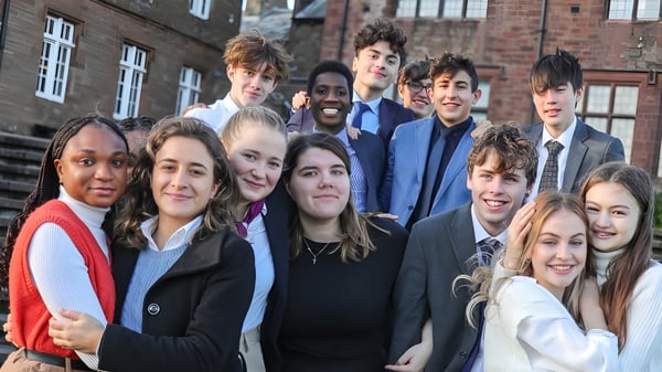 Un grupo de estudiantes sonrientes está frente a un edificio de ladrillo de la St. Bees School.