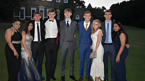Un grupo de personas posando frente al edificio de la St. Brendan’s Community School durante un evento formal.