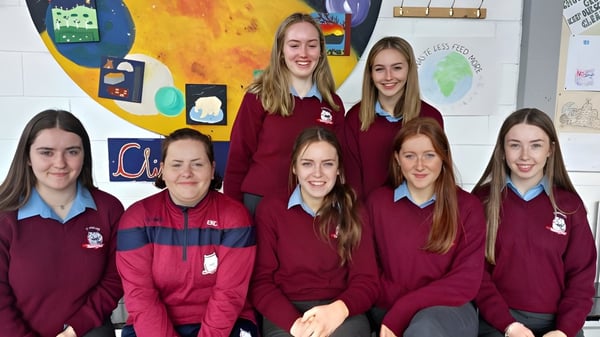 Un grupo de estudiantes femeninas de la St. Brendan’s Community School está frente a un colorido mural.