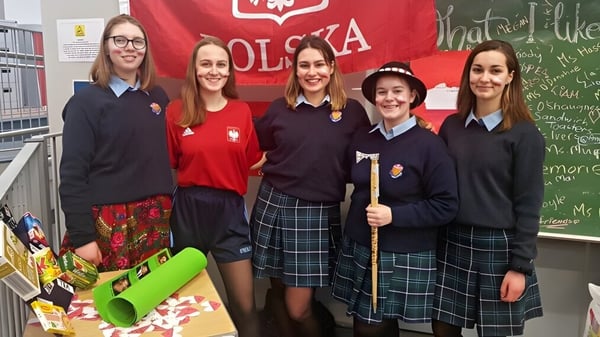 Un grupo de estudiantes de St. Brigid's College está frente a una bandera roja y blanca con el emblema del águila polaca.