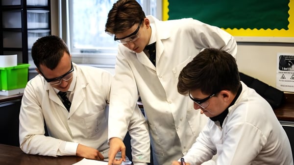 Tres estudiantes de la St. Christopher School examinan juntos una muestra en el laboratorio.